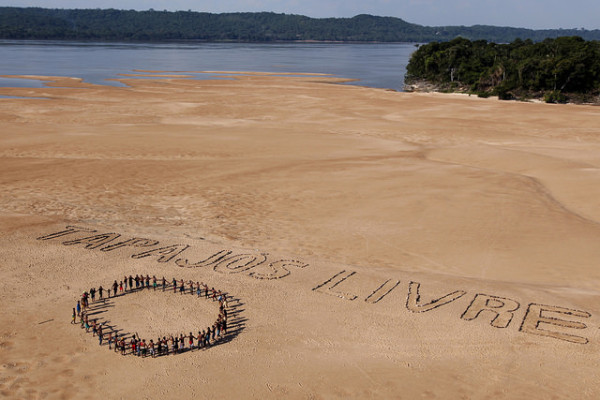 Foto de Marizilda Cruppe, tirada em 26/11/2014, mostrando Ativistas do Greenpeace e índios Munduruku. Pedras formam a frase nas areias de uma praia às margens do rio de mesmo nome, próximo ao município de Itaituba, no Pará. O protesto, que contou com a participação de 60 Munduruku, ocorreu onde o governo pretende construir uma das hidrelétricas projetadas para a bacia do Tapajós.